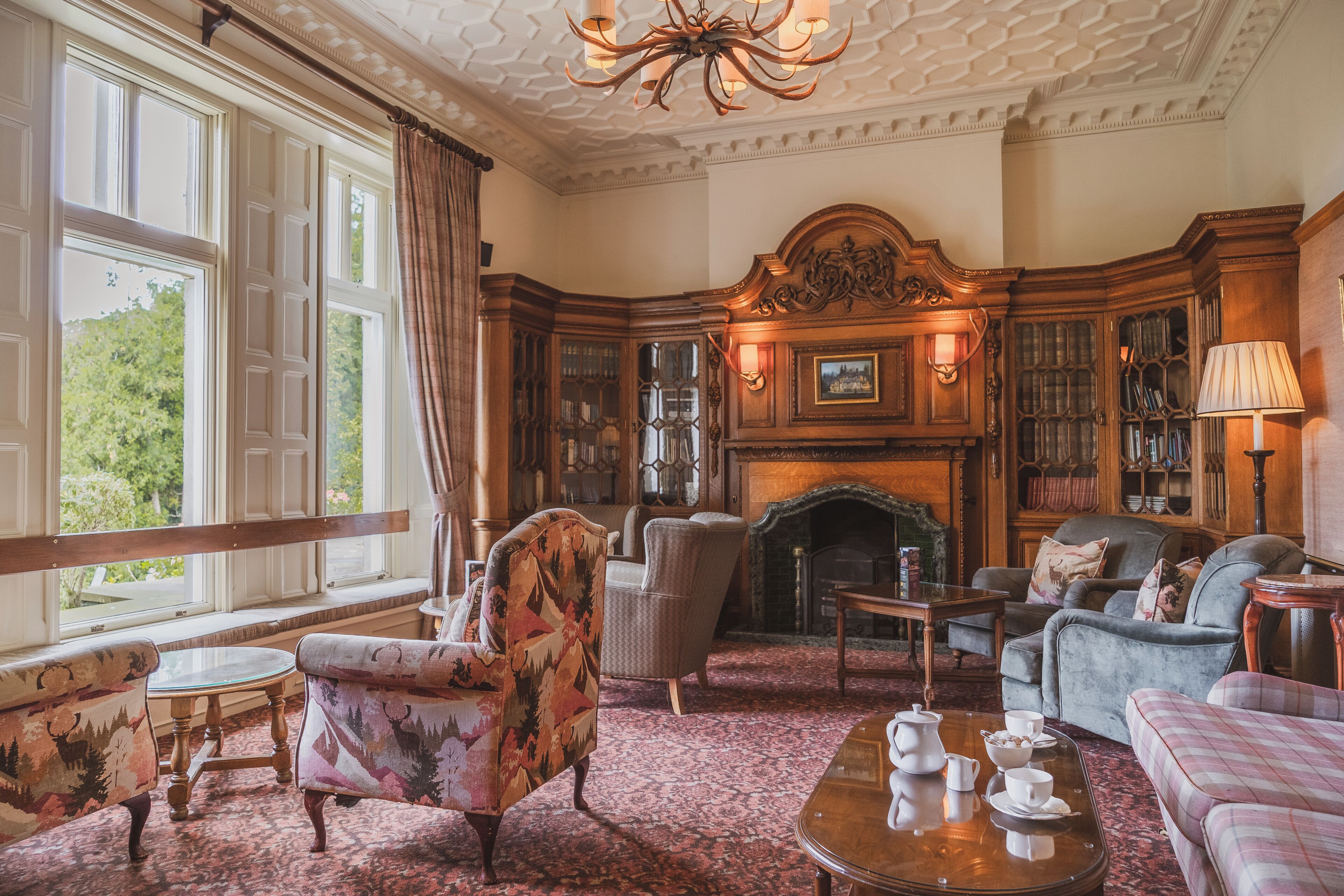 A traditional library room with wooden bookshelves, a fireplace, and comfortable seating.