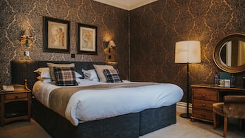 Een slaapkamer met een groot bed, twee wandlampen, een dressoir en een spiegel.