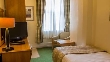 Une chambre d’hôtel comprenant un lit, un bureau avec une télévision, un téléphone et une chaise.