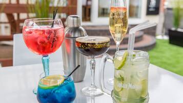 A table with various drinks including a red cocktail, a blue cocktail, a champagne flute, and a pitcher labeled "Captain Morgan".