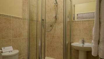 A bathroom with a glass-enclosed shower, a toilet, and a sink.