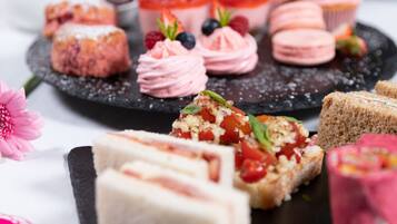 Diversos doces em um suporte de ardósia, incluindo macarons, pastéis e bolos com fruta.