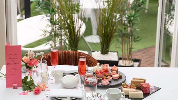 A table set for a tea service with a menu, floral arrangements, and a variety of desserts. - A Park View Hotel (Wolverhampton)