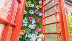 A red telephone booth with a green artificial grass interior and various flowers. - A Park View Hotel (Wolverhampton)