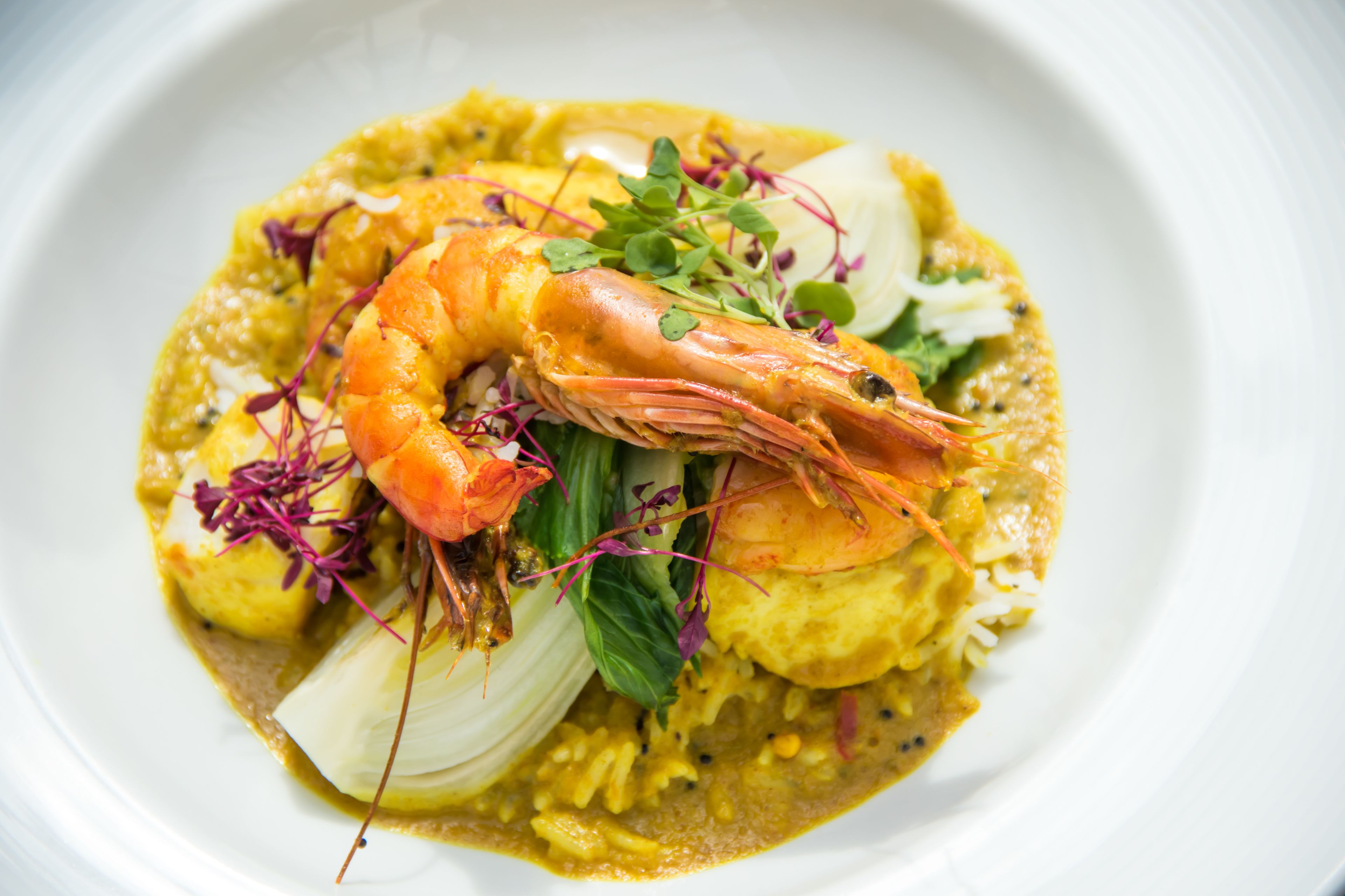 Un plato de comida con camarones, arroz y verduras.