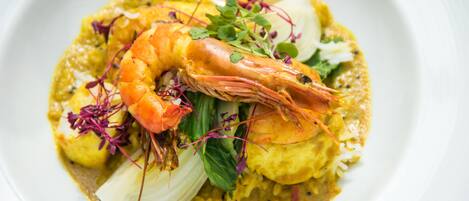 Un plato de comida con camarones, arroz y verduras.