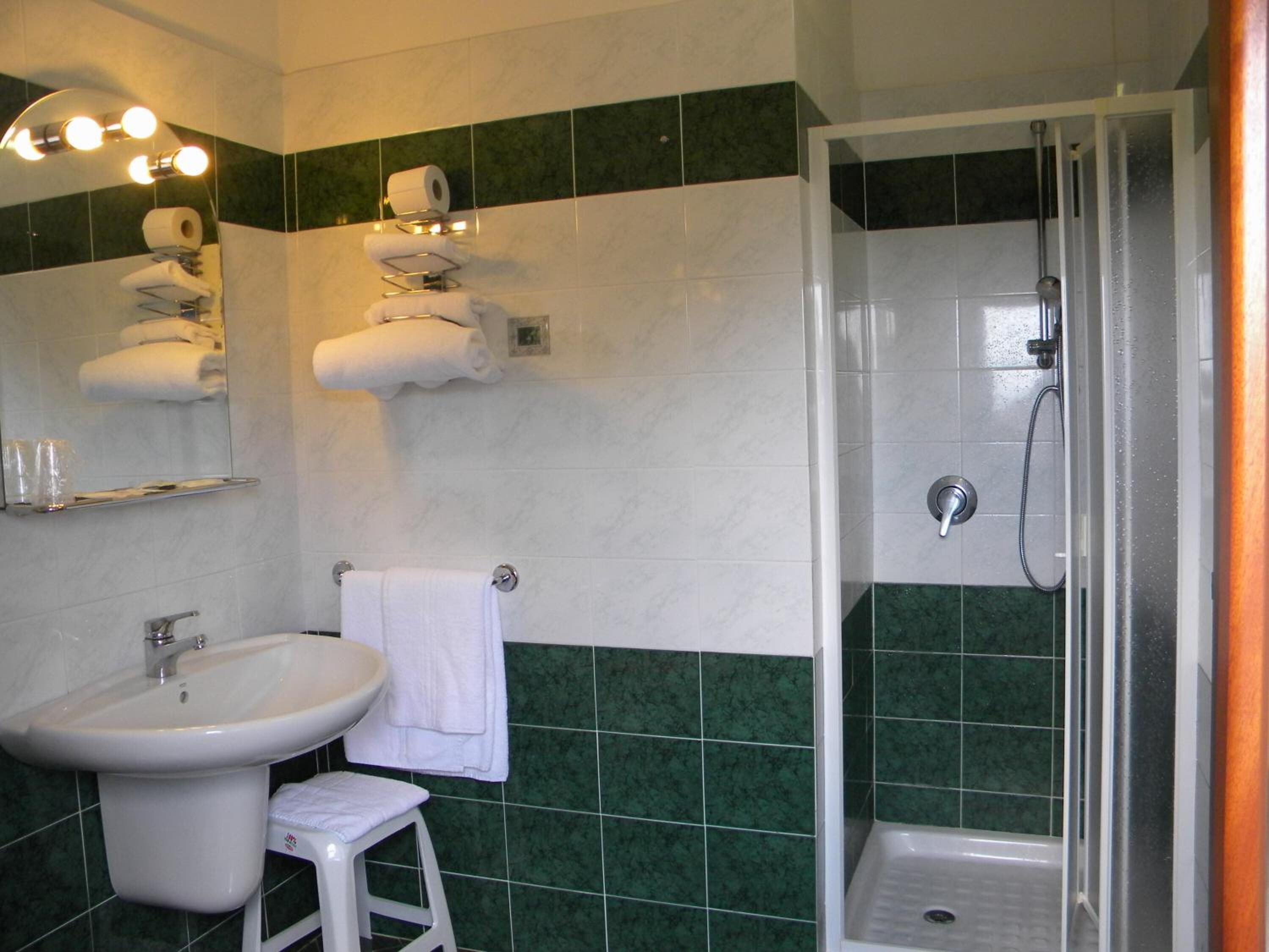A bathroom with a sink, mirror, towel rack, and shower.