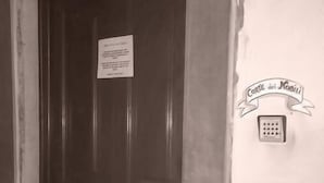 A door with a sign, a keypad, and a wall-mounted device. - Corte dei Nobili (Lucca)