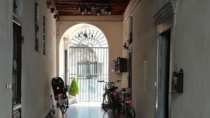 A narrow hallway with tiled flooring, a bicycle, and a stroller. - Corte dei Nobili (Lucca)