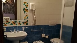 A bathroom with a sink, bidet, toilet, and a mirror with sunflower decorations. - Corte dei Nobili (Lucca)