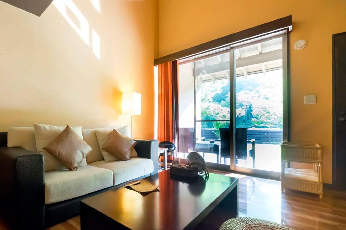 Sala de estar com sofá, mesa de centro e vista para uma varanda.