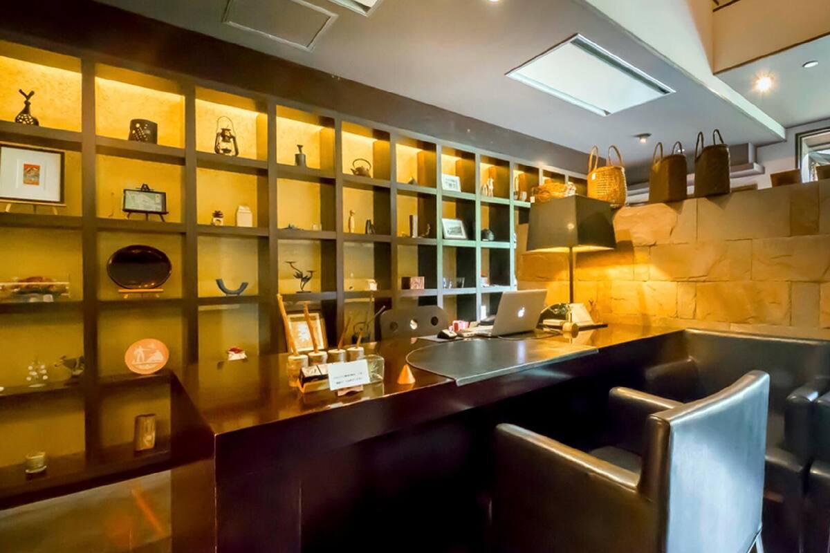 Uma área de bar moderna com um laptop, banquetas e prateleiras com diversos objetos.