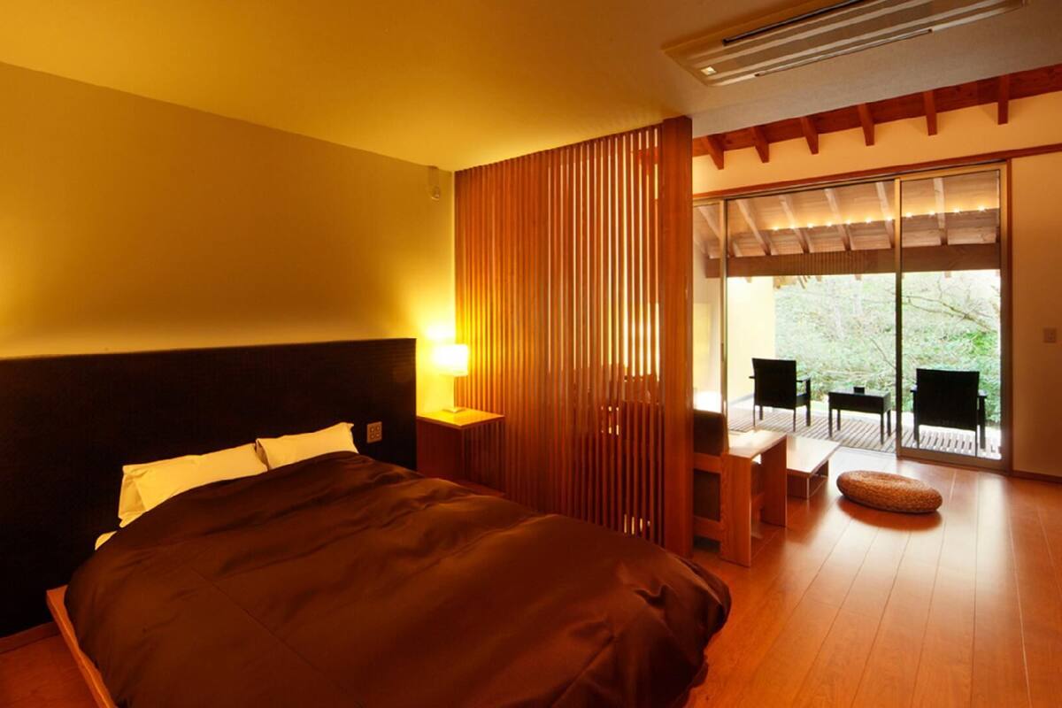 Quarto moderno com uma cama grande, abajures e uma porta de vidro deslizante para uma varanda.
