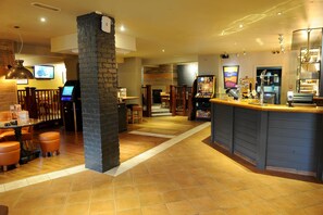 A bar area with a counter, stools, and a television screen. - Premier Inn York North West (York)