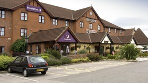 A hotel with a 'Premier Inn' sign, a 'Beefeater' sign, and a 'Pillars' sign. There is a car parked in front. - Premier Inn York North West (York)