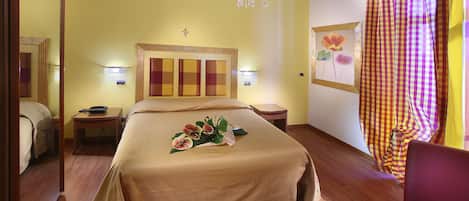 A hotel room with a large bed, bedside tables, a chandelier, and a checkered curtain.