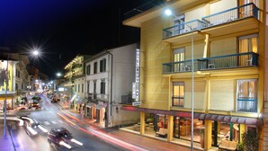 Ein Hotel mit mehreren Balkonen, einem sichtbaren Garagenschild und Straßenszene mit Autos und Lichtern.