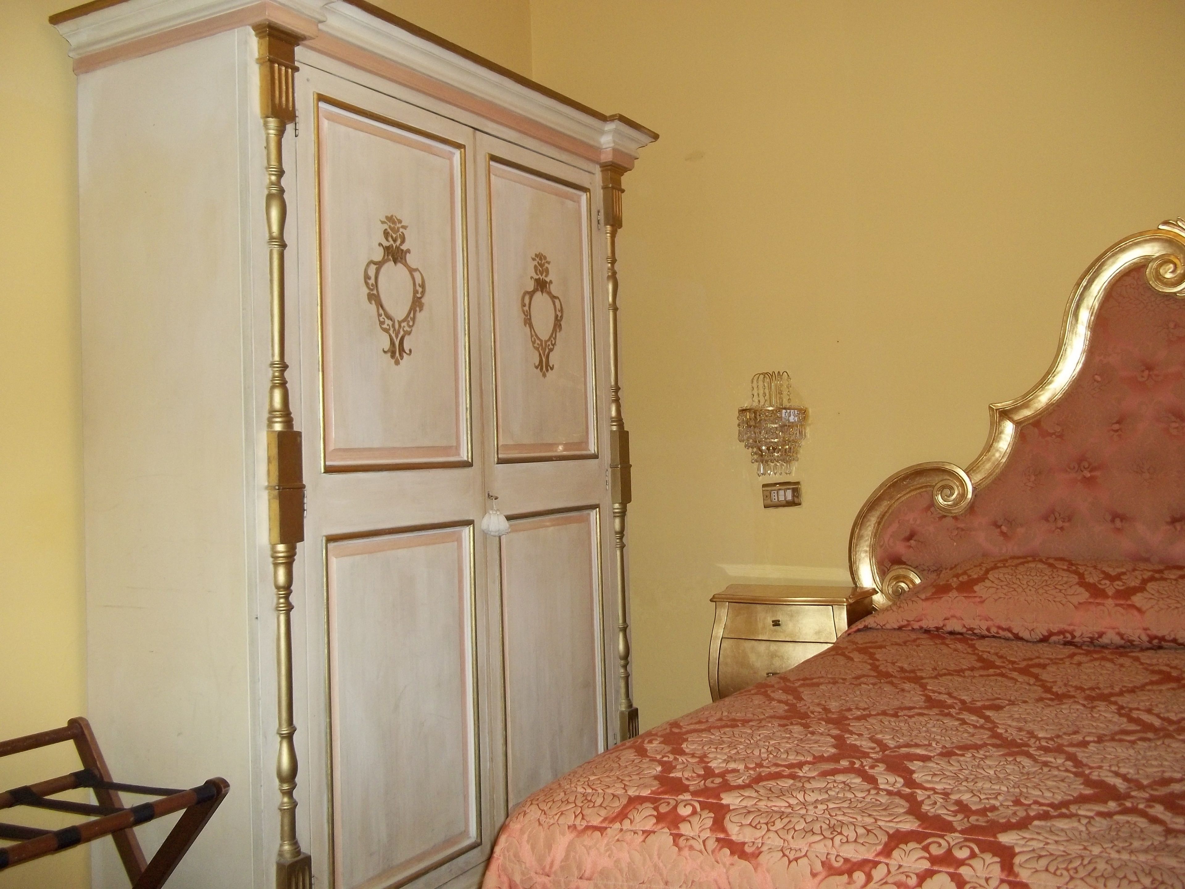 Een slaapkamer met een grote inbouwkast, een bed met een bloemenbedekking en een wandlamp.