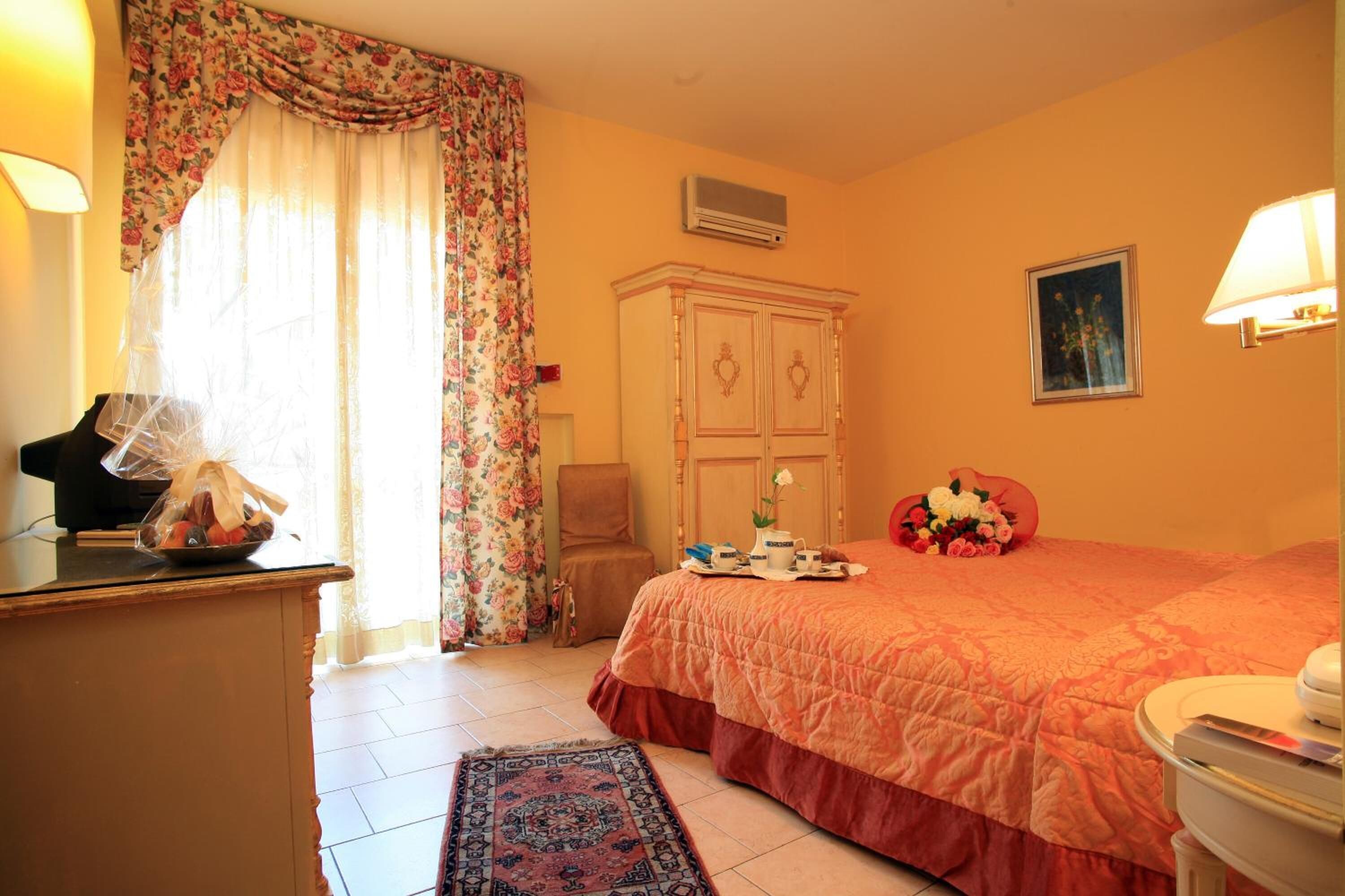 Ein Schlafzimmer mit Bett, Kommode, Stuhl, Schreibtisch und einem fenster mit Vorhängen.