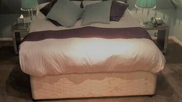 A single bed in a room with a sloped ceiling, two bedside tables with lamps, and a telephone.