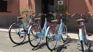 Une rangée de vélos bleu clair est garée devant un bâtiment sur lequel on peut lire l’inscription « HÔTEL EST ».