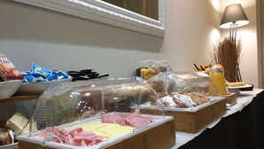Un buffet proposant une variété de plats, notamment des viandes et des pâtisseries, présentés sous des cloches de verre.