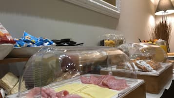 Un bufé con diversos alimentos, incluyendo carnes y quesos, cubiertos con campanas de plástico.