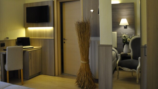Une chambre d’hôtel équipée d’un bureau, d’une chaise, d’une télévision et d’un balai décoratif.