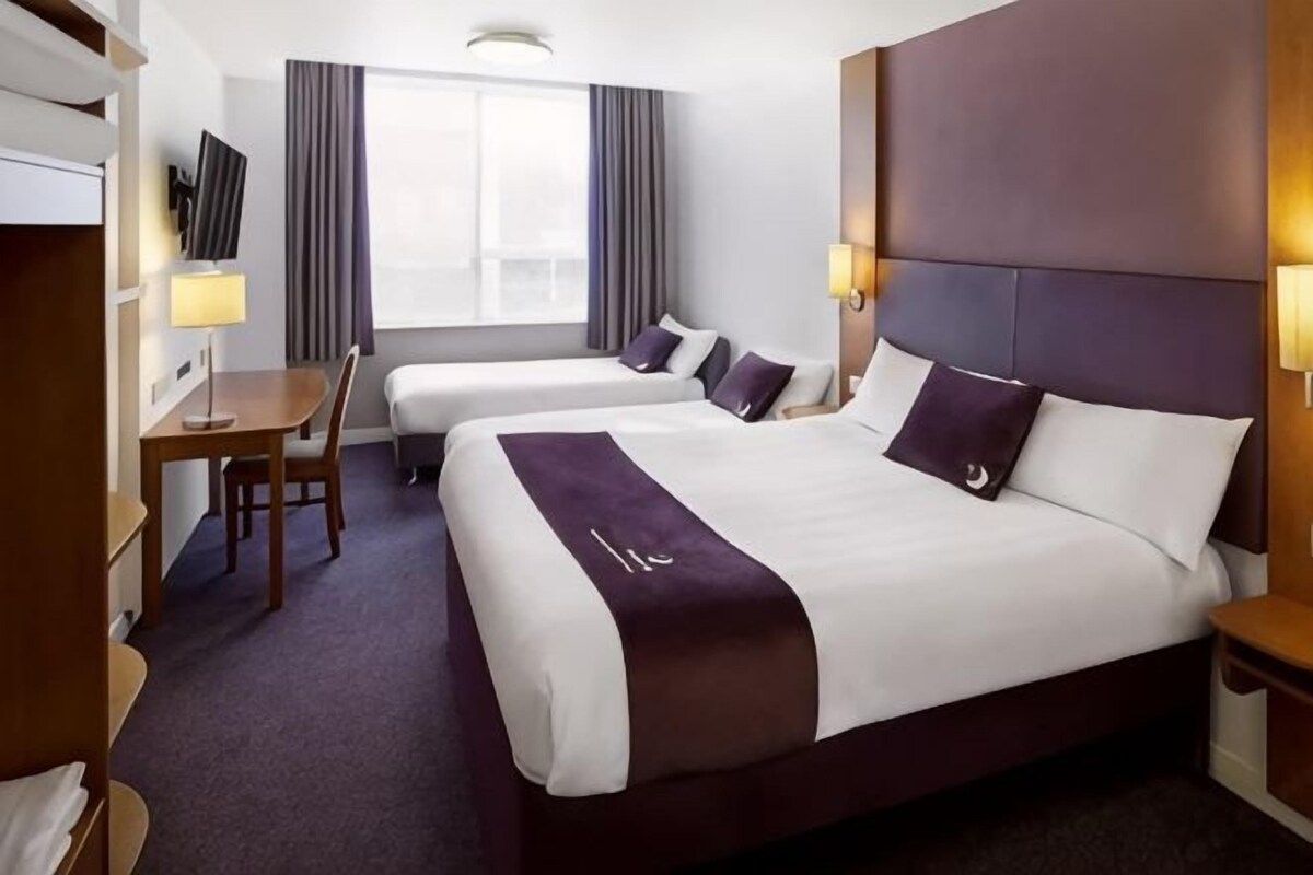A hotel room with two beds, a desk, and a TV.