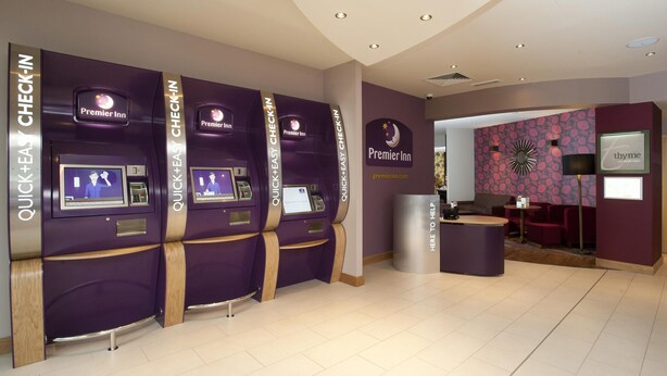 A hotel reception area with Premier Inn check-in kiosks, a help desk, and a Thyme restaurant sign. - Premier Inn Belfast Titanic Quarter (Belfast)