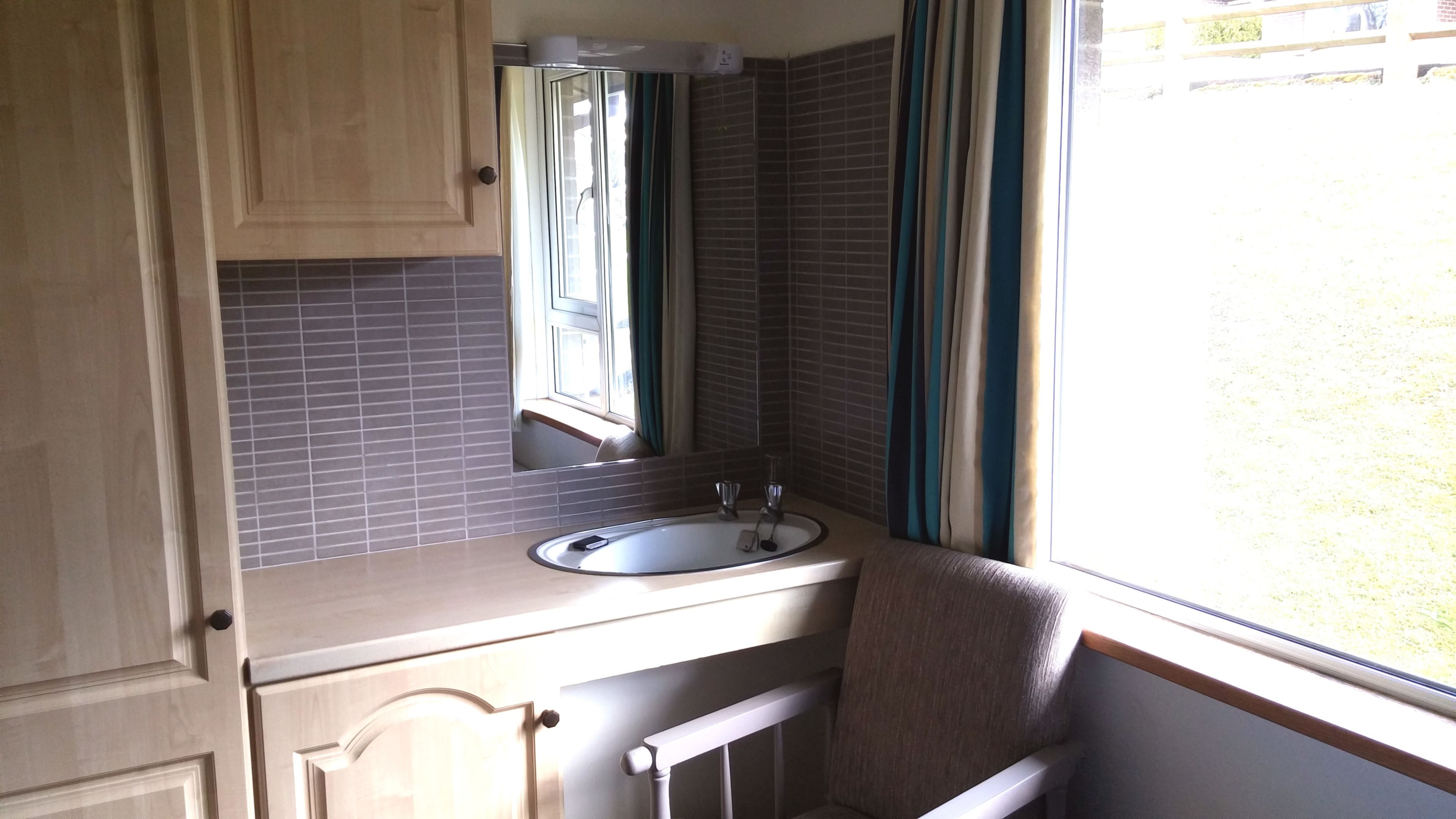 A compact bathroom with a sink, mirror, and window.