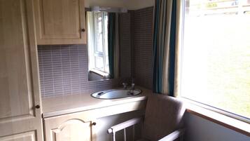 A compact bathroom with a sink, mirror, and window.