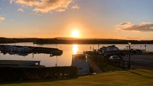 Ein Yachthafen mit vor Anker liegenden Booten, ein Weg zu einem Boot und ein Sonnenuntergang im Hintergrund.