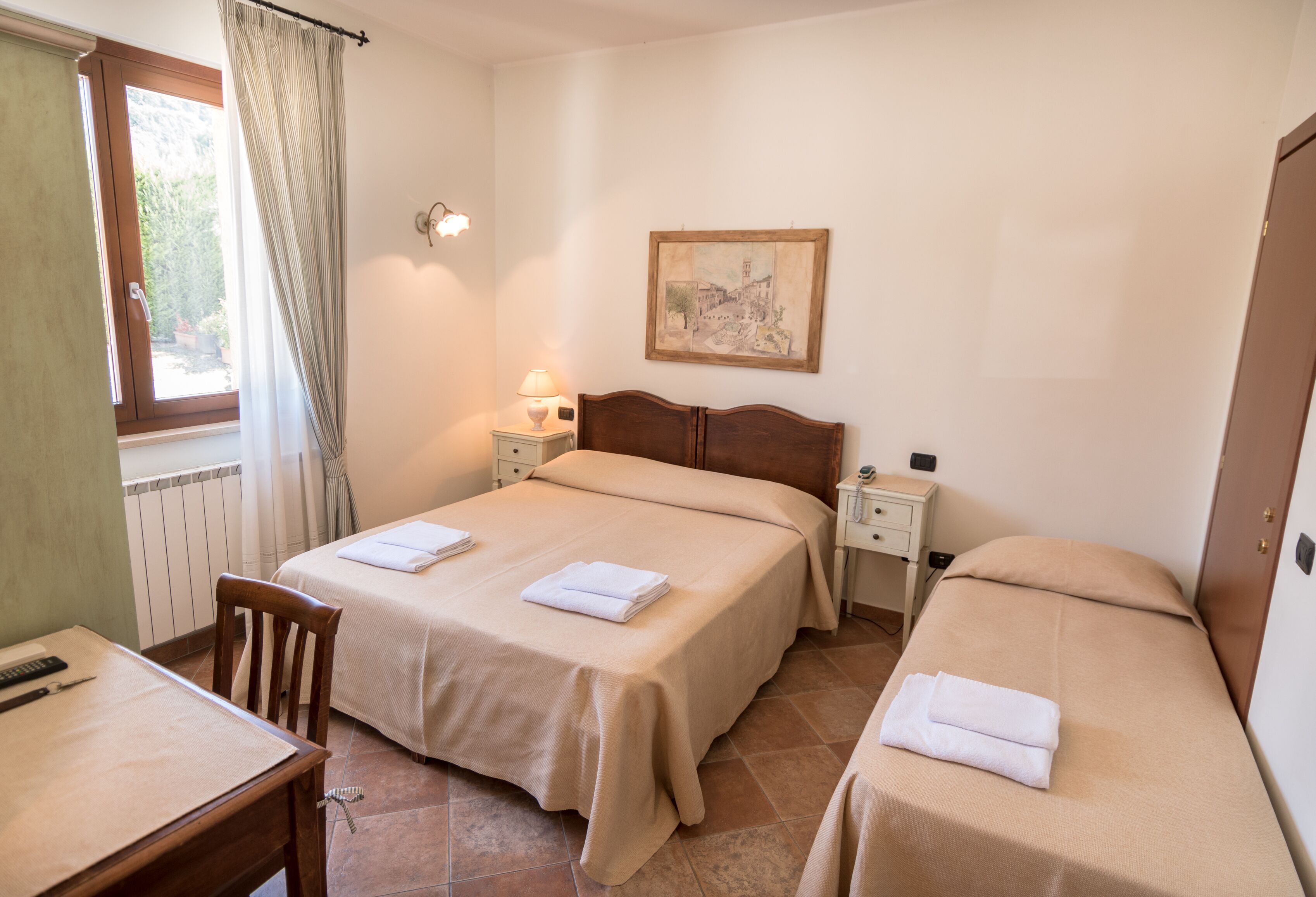 A hotel room with two beds, a table, and a chair.