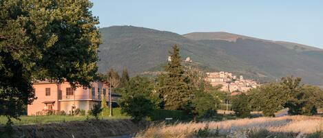 A rural road leading to a small town with buildings on a hill.