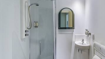 Un baño moderno con ducha envuelta en vidrio, lavamanos y espejo.