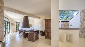 A spacious room with a stone wall, a wooden cabinet, and a large hanging light fixture.