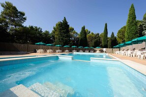 Una piscina al aire libre, sillones reclinables de piscina