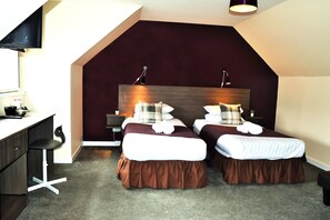 Une chambre d’hôtel moderne avec deux lits, un bureau et une chaise.