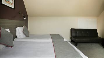 Habitación de hotel con dos camas, un sofá, una lámpara de pared y una puerta.