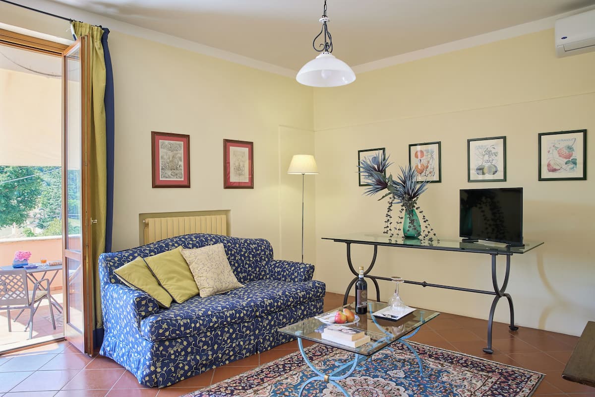 A living room with a sofa, a glass coffee table, a TV, and framed artwork on the wall.