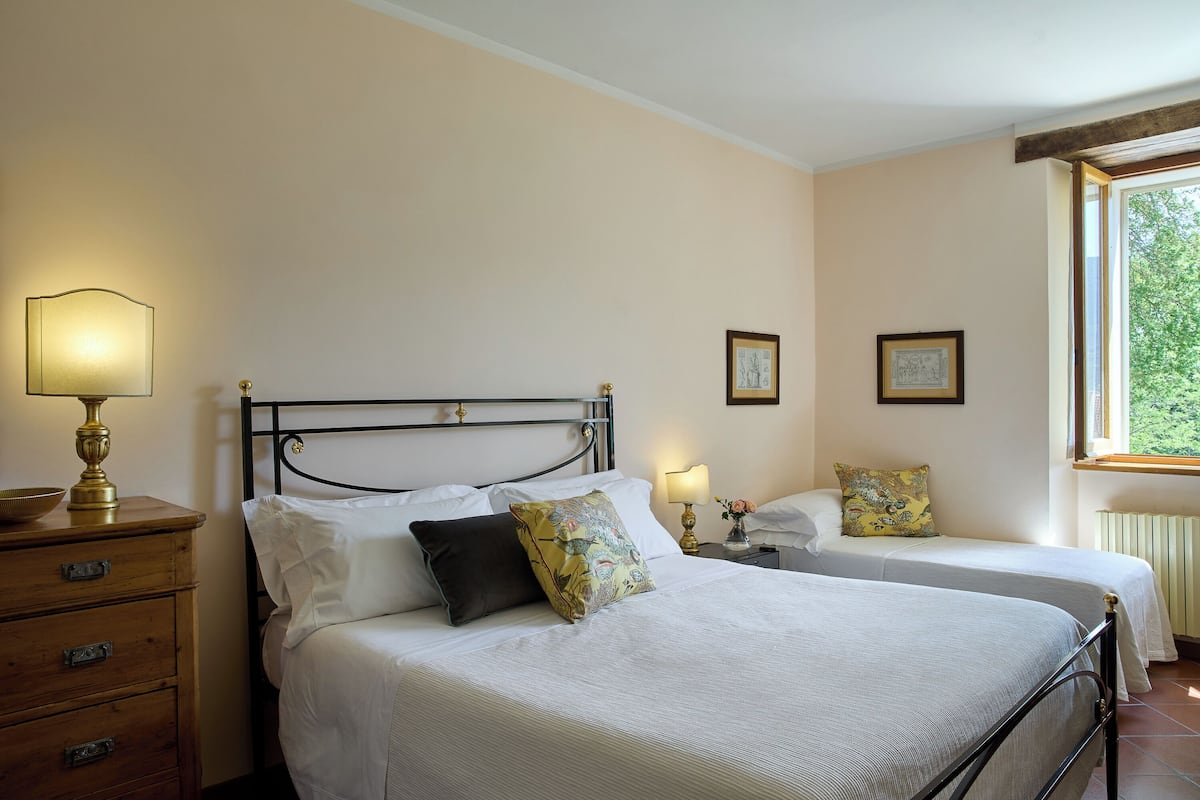 A bedroom with two single beds, a wooden dresser, bedside lamps, and framed pictures on the wall.