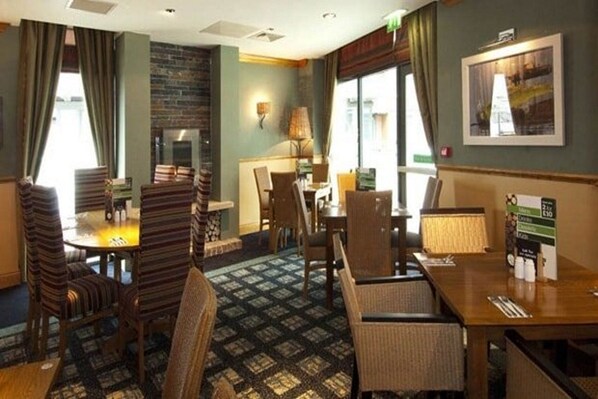 A hotel room with a dining area, a fireplace, and a view of the city. - Premier Inn Glasgow (Glasgow)