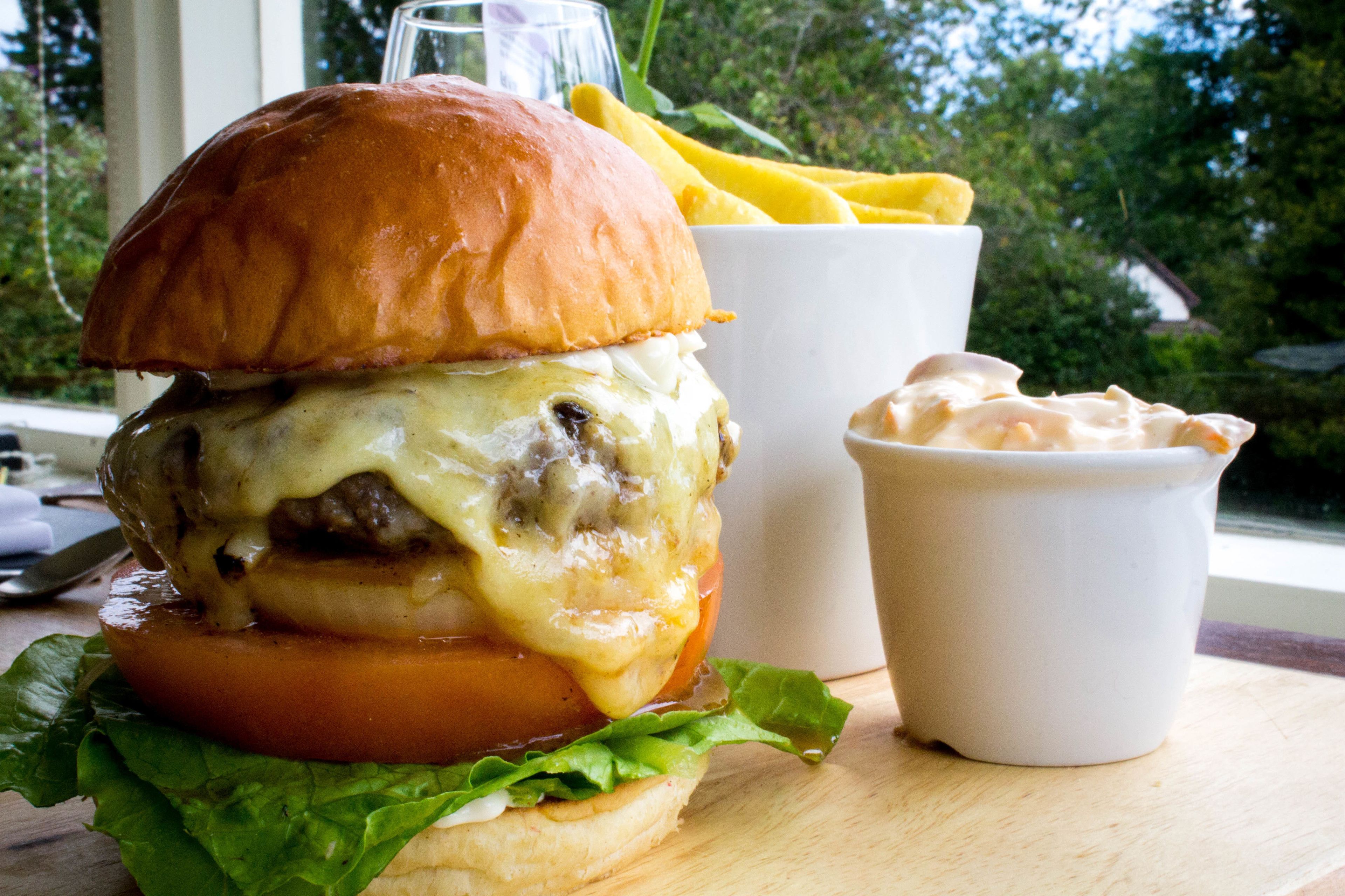 A burger with fries and a drink on a wooden table.