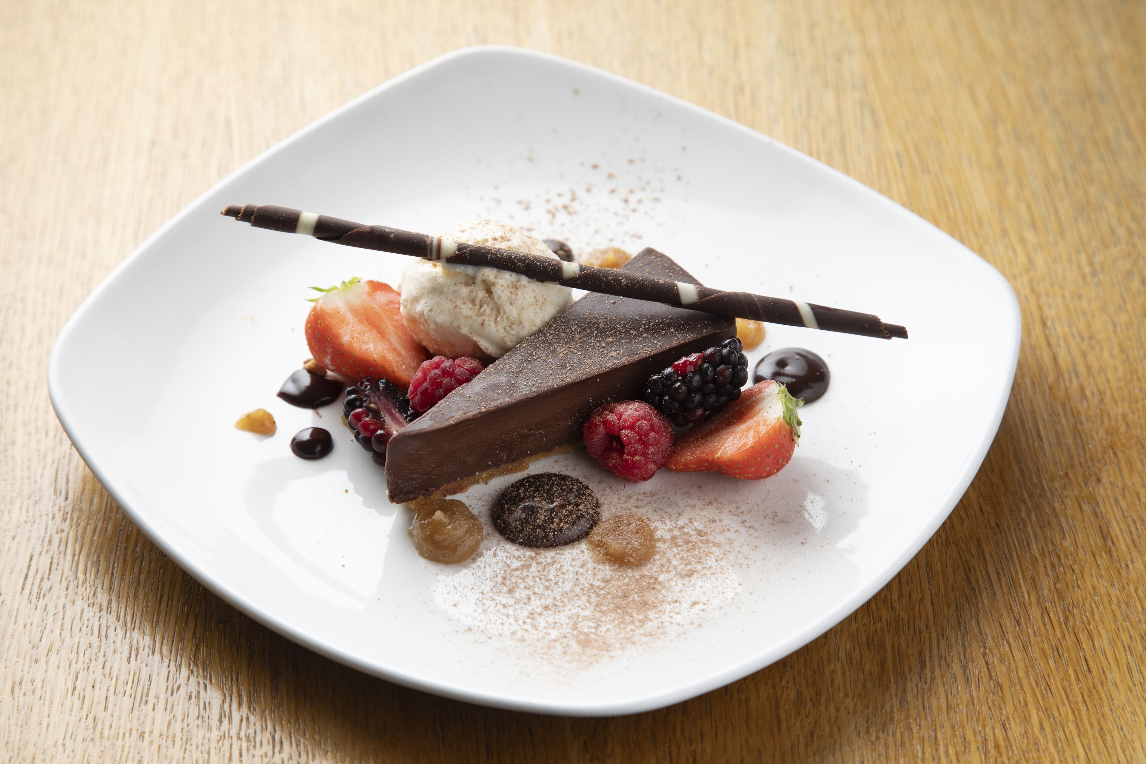 A dessert plate with chocolate, strawberries, raspberries, and other fruits on a white plate.