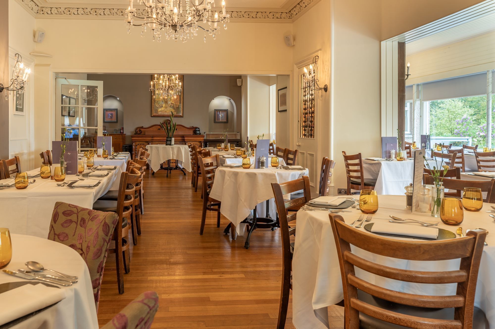 Un comedor con varias mesas, sillas y candelabros.