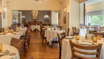Un comedor con varias mesas, sillas y candelabros.