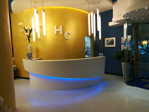 A reception desk with a curved design, illuminated by vertical light fixtures and a blue underglow.