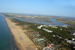 Luchtbeeld van een kustgebied met strand, een jachthaven en woongebouwen.