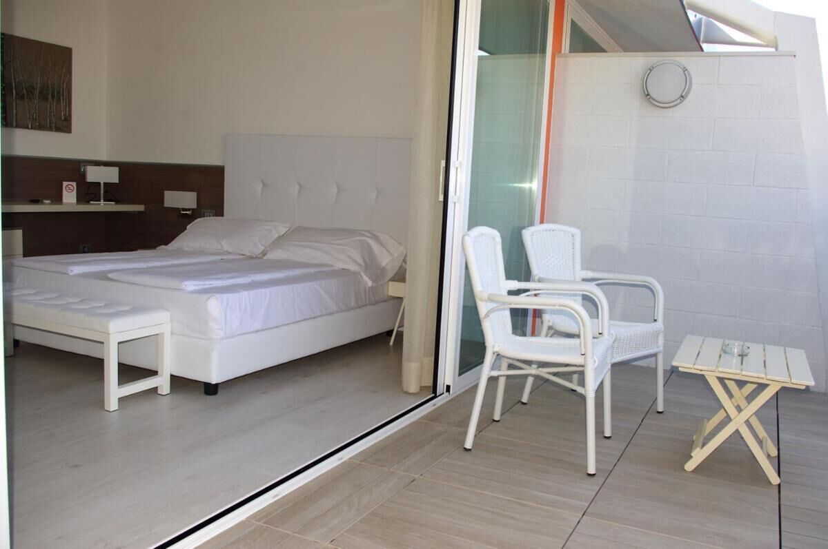 A bedroom with a bed, a bedside table, a chair, and a small table.